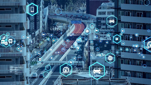 Paesaggio urbano denso di traffico sovrapposto a grafiche digitali futuristiche per indicare la connettività e lo scambio di dati tra veicoli e infrastrutture.