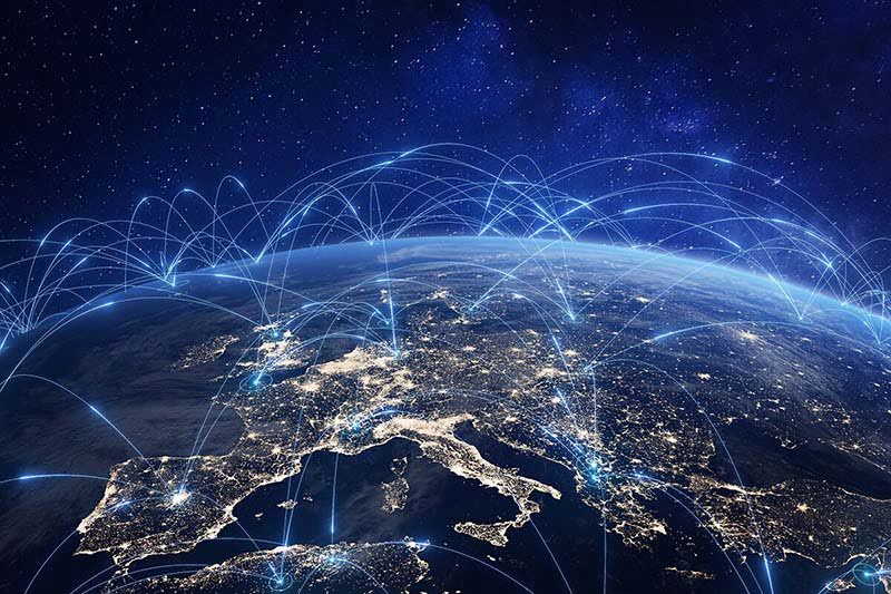 Reti di comunicazione wireless visualizzate come bande di luce che si propagano da una città all'altra attraverso un'immagine satellitare dell'Europa notturna.